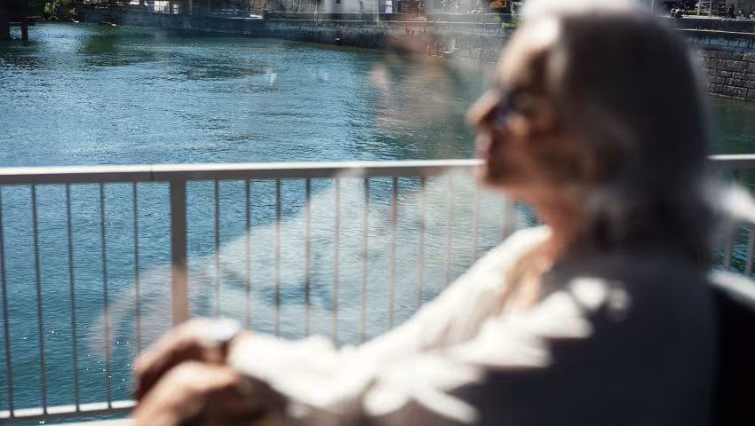 Frau blickt aus einem Busfenster, dahinter ist die Aare zu sehen.